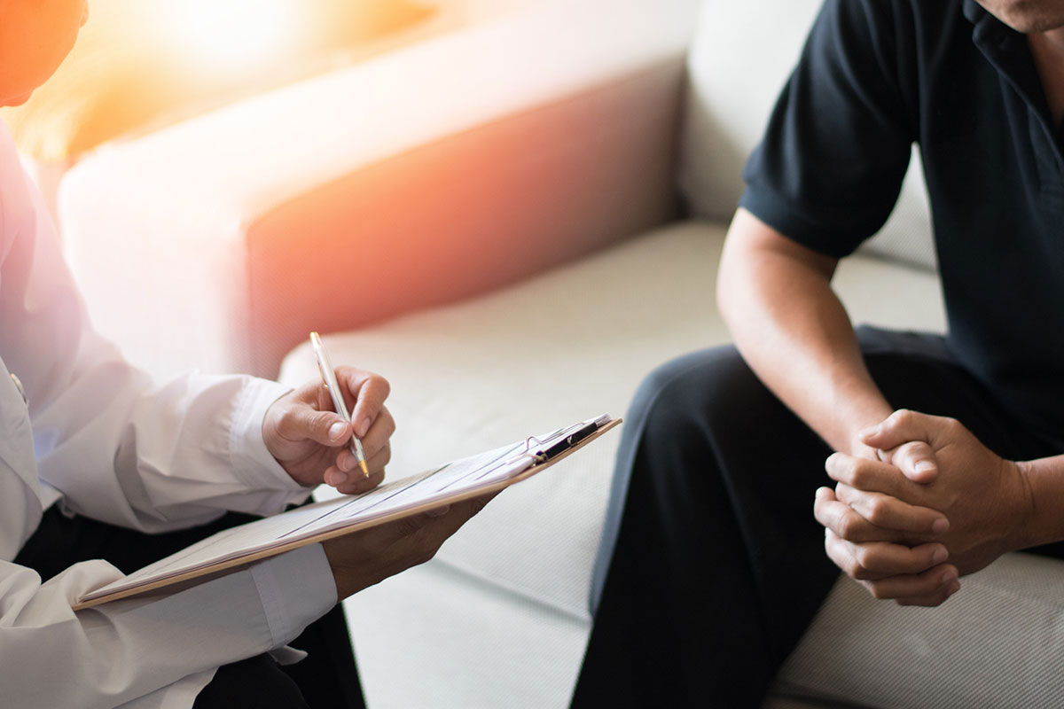 A close up of a patient's arms and a counselor's arm and clipboard.