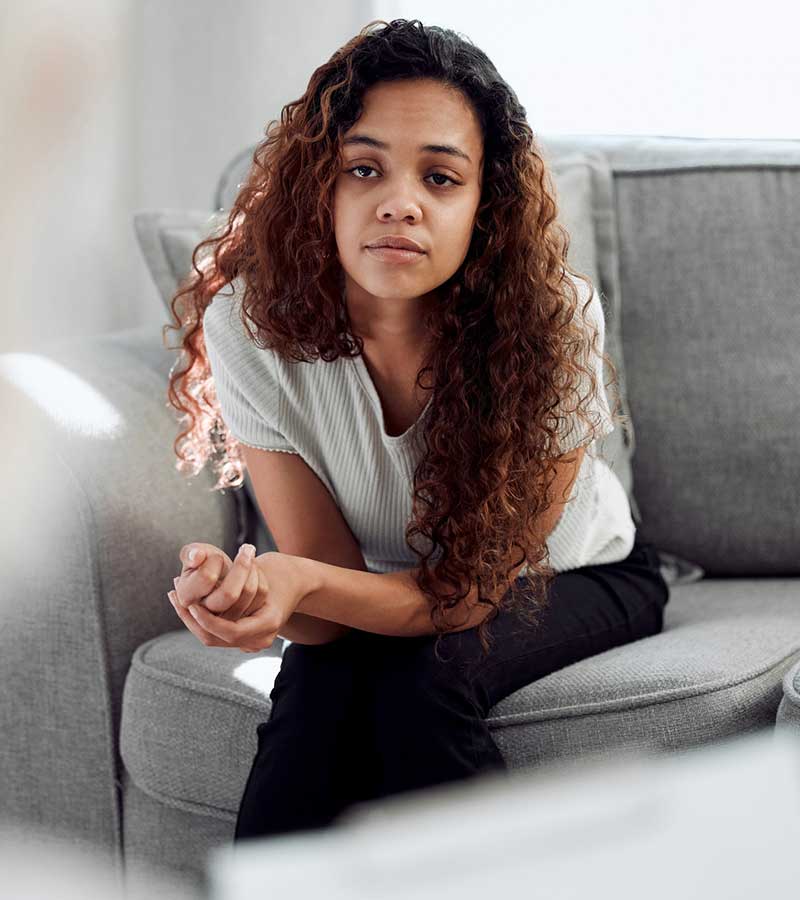 A young woman staring into the camera with a tired, sad expression.